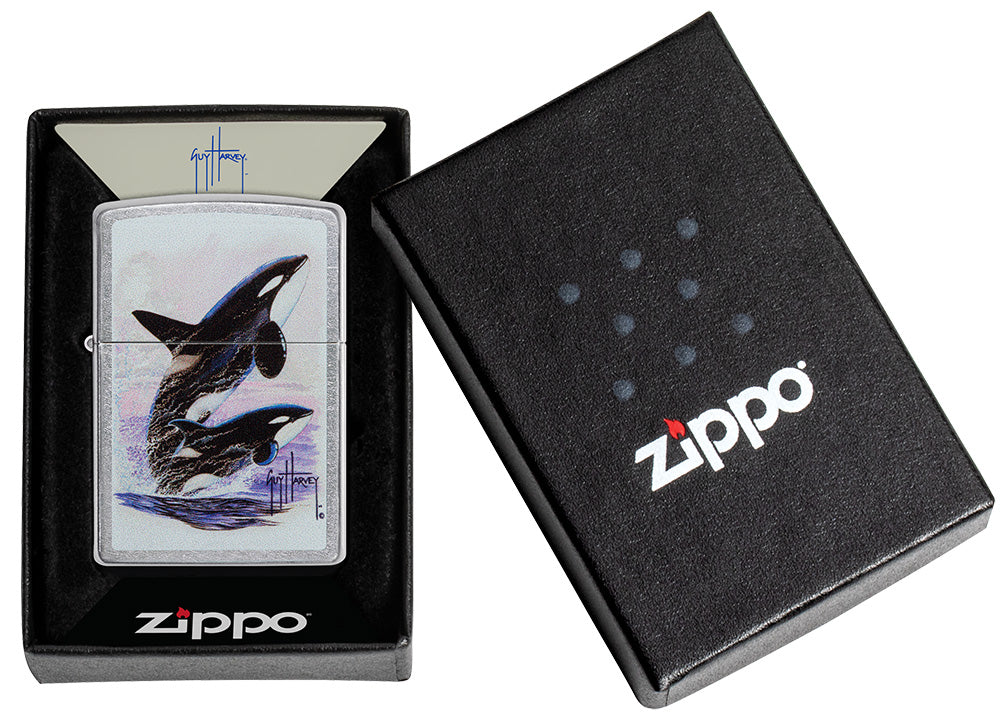 Encendedor Zippo vista frontal cromado con ilustración coloreada de dos orcas dibujadas por Guy Harvey en caja abierta