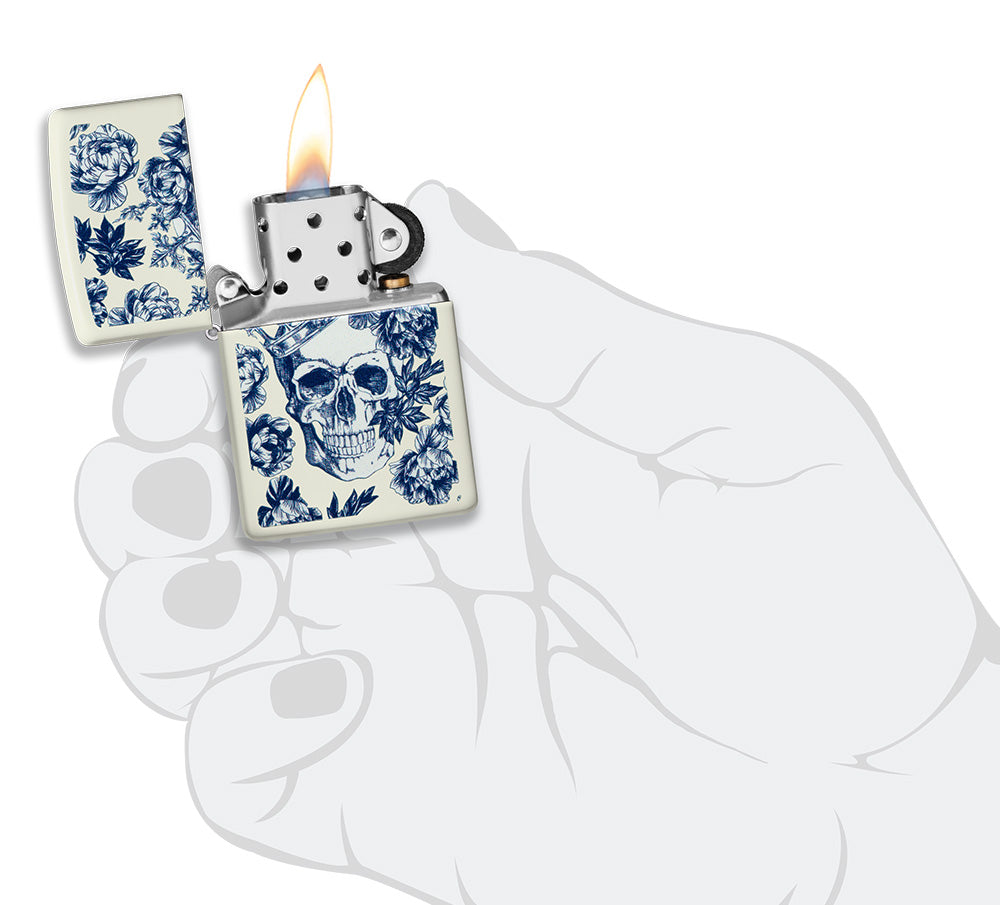 Encendedor Zippo que brilla en la oscuridad calavera con corona rodeada de flores azules abierta con llama en mano estilizada