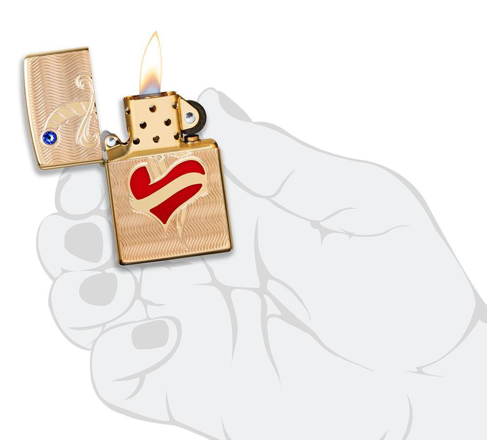 Briquet Zippo Armor en laiton cœur rouge avec poignard et pierre Swarovski, ouvert avec flamme dans une main stylisée