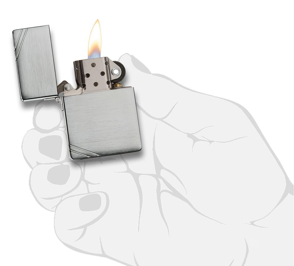Réplica del encendedor Zippo 1935 vista frontal abierta y encendida en aspecto de cromo cepillado con barras grabadas en las esquinas opuestas en mano estilizada.