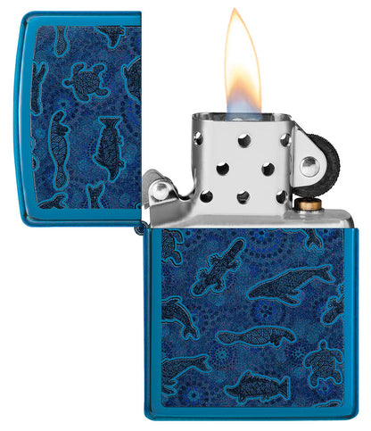 Encendedor Zippo de vista frontal abierto y encendido en azul de alto brillo con ilustración de criaturas marinas al estilo del arte aborigen.