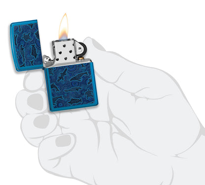 Encendedor Zippo con vista frontal abierta y encendida en azul de alto brillo con ilustración de criatura marina de estilo artístico aborigen en mano elegante