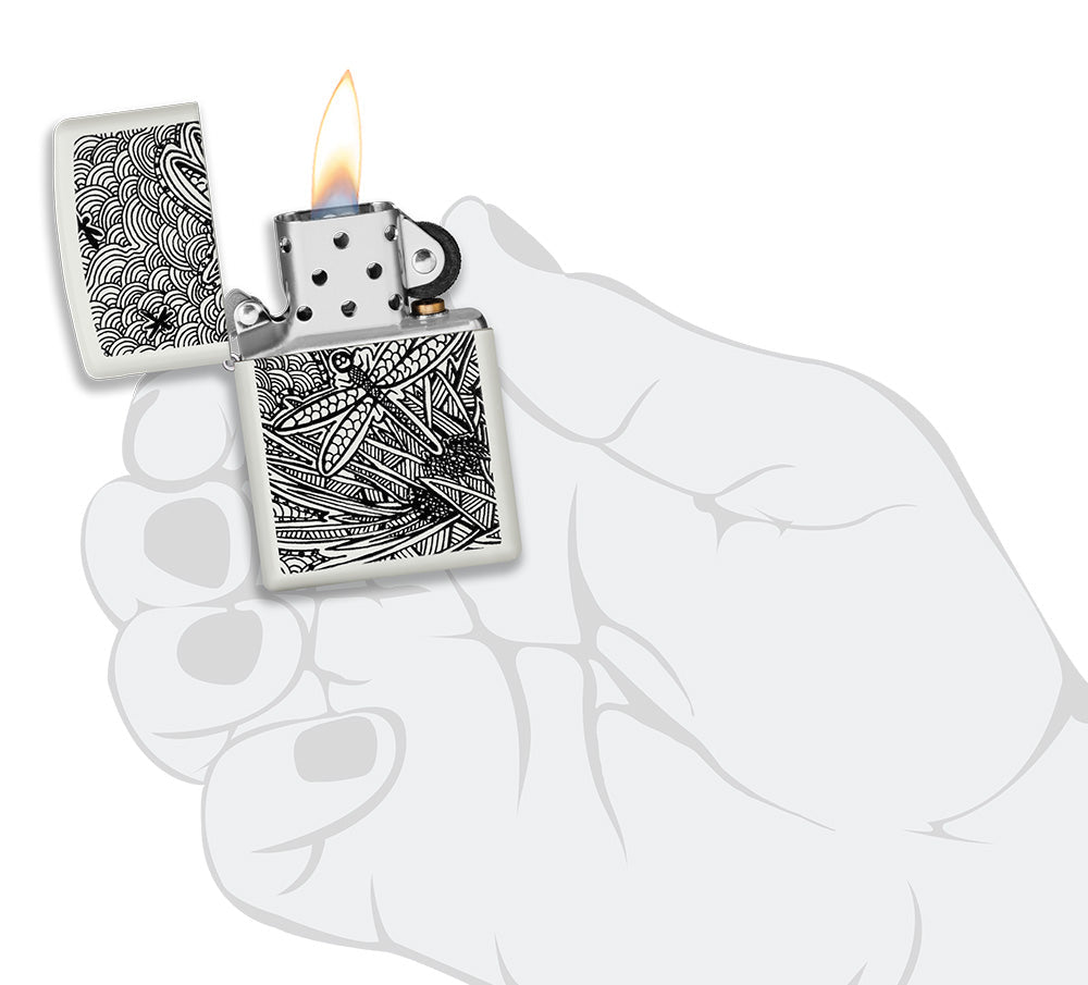 Encendedor Zippo vista frontal blanco mate abierto y encendido con la ilustración de una libélula en el estilo del arte aborigen en la mano estilizada