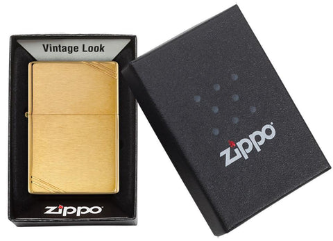 Vue de face briquet Zippo Vintage Brass Brushed avec des entailles décoratives aux deux coins, dans une boîte cadeau ouverte