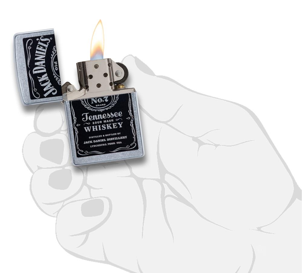 Briquet Zippo chromé avec logo Jack Daniel's noir, ouvert avec flamme dans une main stylisée
