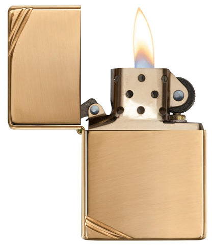 Vue de face briquet Zippo Vintage Brass High Polished avec des entailles décoratives aux deux coins, ouvert avec flamme
