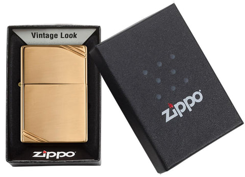 Vue de face briquet Zippo Vintage Brass High Polished avec des entailles décoratives aux deux coins, dans une boîte cadeau ouverte