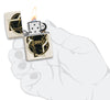 Encendedor Zippo abierto y encendido con aspecto de Mercury Glass blanco con forma jaspeada de oro negro en el centro entrelazada con una línea blanca y otra negra en mano estilizada