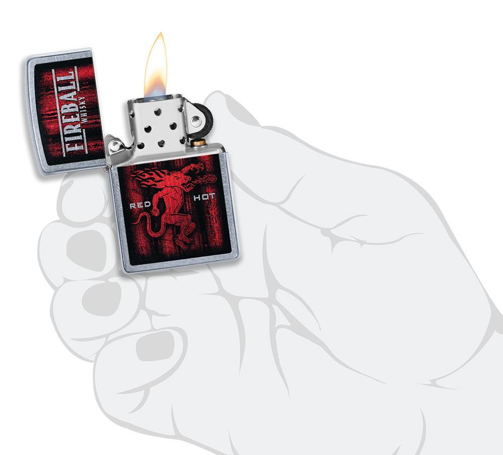  Briquet Zippo chromé whisky Fireball, ouvert avec flamme dans une main stylisée