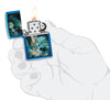 Encendedor Zippo azul brillante en un escenario místico con una dama ligeramente vestida en el lago rodeada de calaveras así como cuervos abiertos con la llama en la mano estilizada