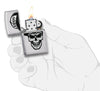 Briquet Zippo chromé tête de mort avec casquette Zippo, ouvert avec flamme dans une main stylisée
