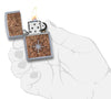 Briquet Zippo Woodchuck carte et boussole, ouvert avec flamme dans une main stylisée