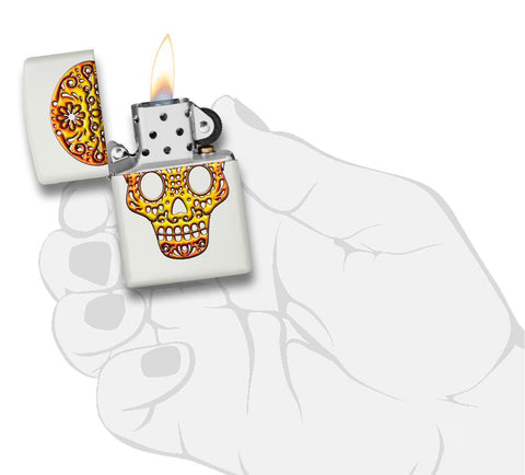 Briquet Zippo blanc avec tête de mort mexicaine, ouvert avec flamme dans une main stylisée