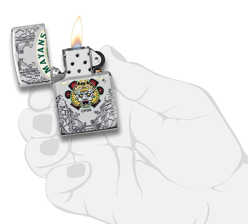 Briquet Zippo chromé avec gravures profondes Mayans M.C., ouvert avec flamme dans une main stylisée