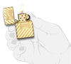 Briquet Zippo laiton haute brillance logo Zippo rétro et rayure transversale gravés, ouvert avec flamme dans une main stylisée