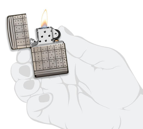 Vue de face briquet Zippo Black Ice avec motif cartes à jouer, ouvert avec flamme dans une main stylisée