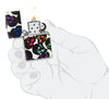 Encendedor Zippo vista frontal Diseño de calaveras con unas calaveras multicolores brillando en la noche en mano estilizada